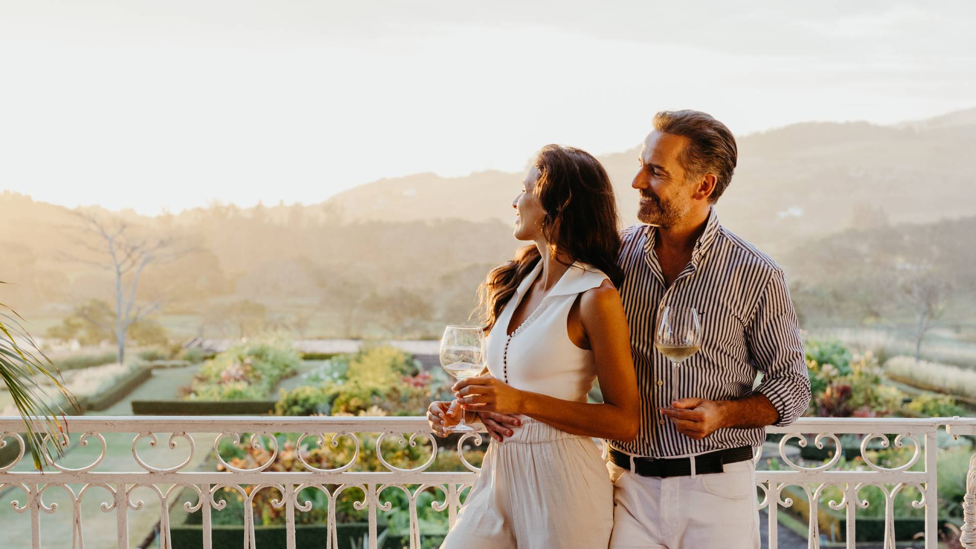 Couple enjoying a sundowner cocktail experience at Le Château de Bel Ombre during sunset with a relaxed and elegant atmosphere